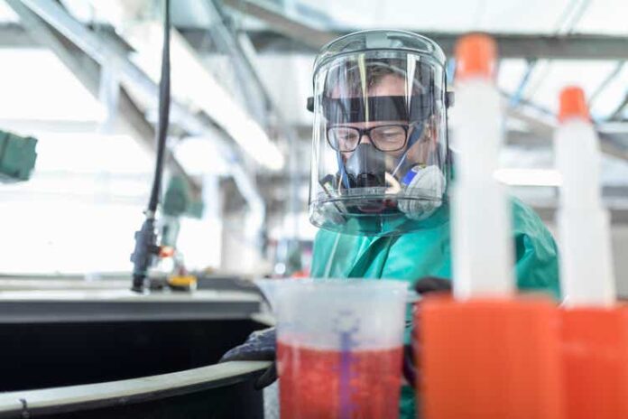 Worker pouring chemical into mixing tanks in chemical factory