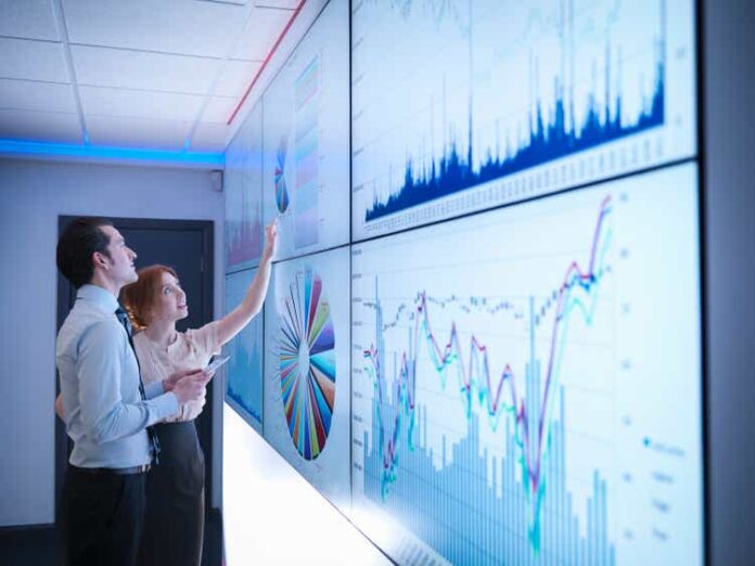 Business colleagues studying graphs on screen in meeting room