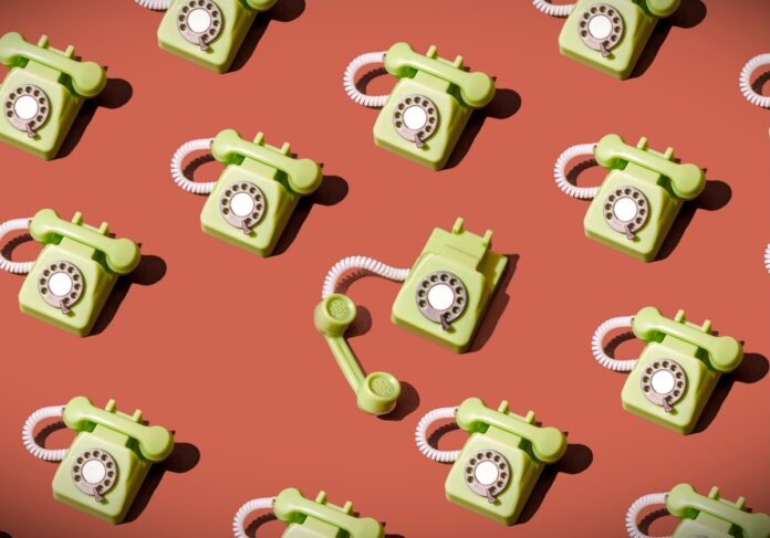 High angle view of some vintage green rotary telephones arranged on a brown background, showcasing retro communication technology with a nostalgic and artistic flair