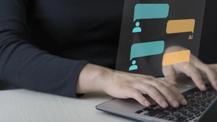A person&apos;s hands type on a laptop keyboard with chat bubbles for a conversation with an AI superimposed above.