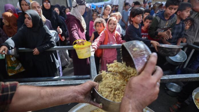 Palestinian children gather to receive food from a charity kitchen in the Gaza Strip