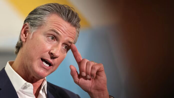 California Governor Gavin Newsom gestures while speaking, with his hand raised near his temple.