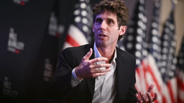 Shaun Maguire speaks, gesturing with his hands, at an event in Washington, DC with US flags in the background.