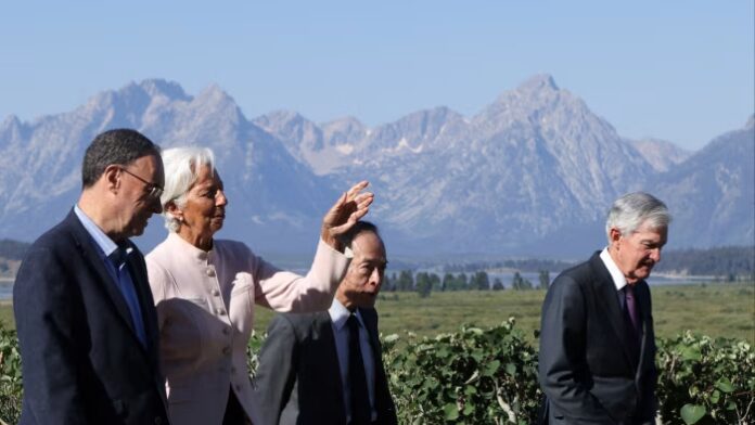 Andrew Bailey, Christine Lagarde, Kazuo Ueda, and Jerome Powell walk outdoors with mountains in the background at Jackson Hole.