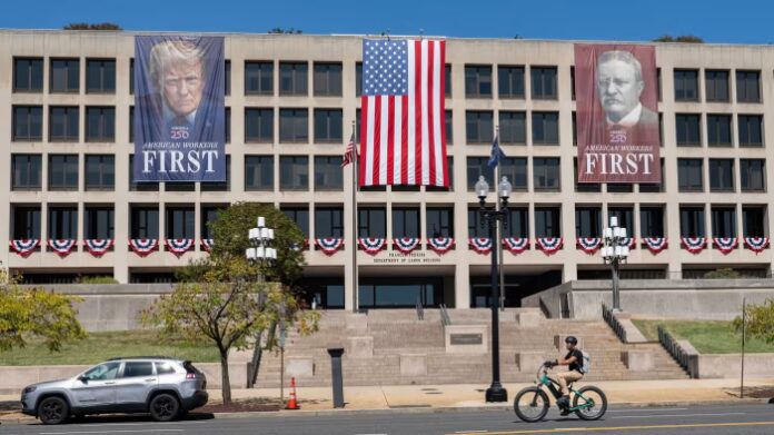Large banners with photos of Donald Trump and Theodore Roosevelt hang on the Department of Labor building, alongside a large American flag.